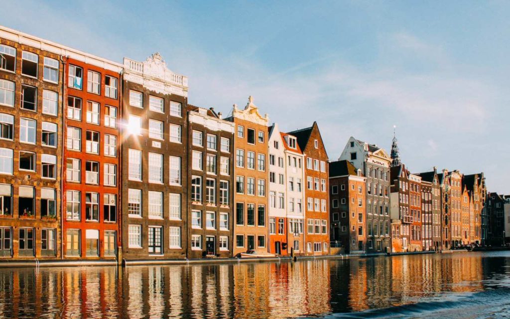 Amsterdam; Alt tekst: Zgrade šarenih fasada na obali reke u Amsterdamu