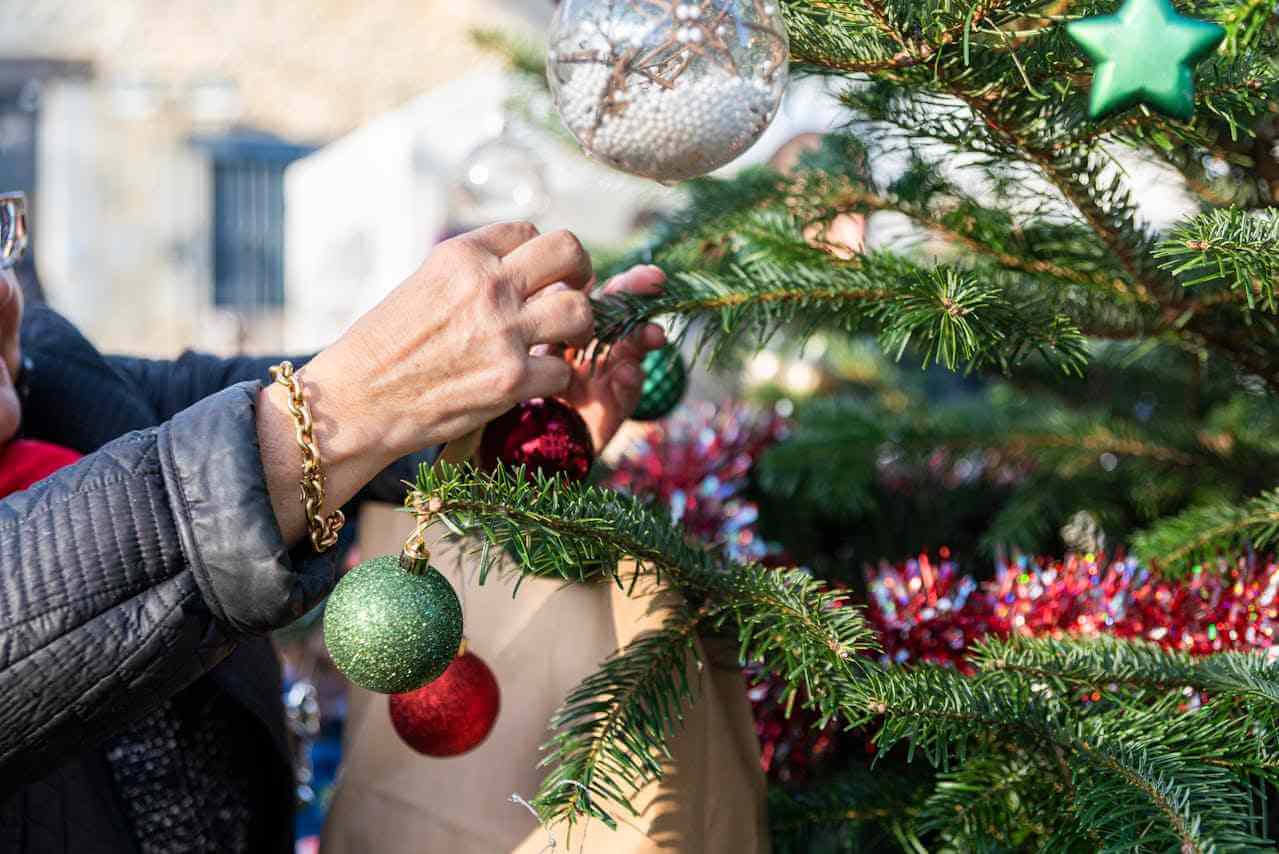 Novogodišnja jelka i ruke žene koja stavlja ukras na jelku