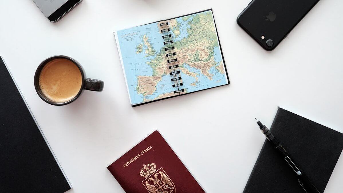 Pasoš, mobilni telefon, blokče i hemijska olovka na stolu