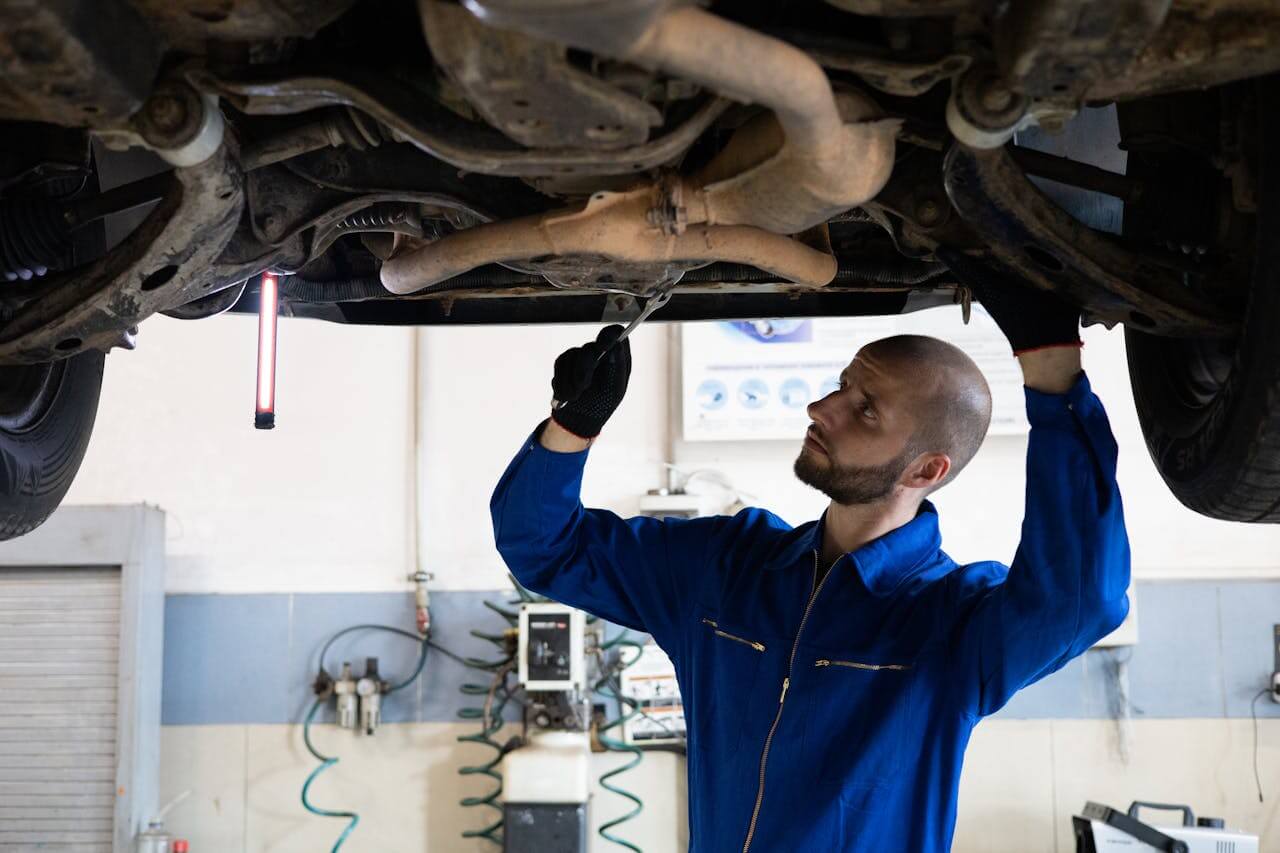 Auto-mehaničar u plavom odelu popravlja automobil