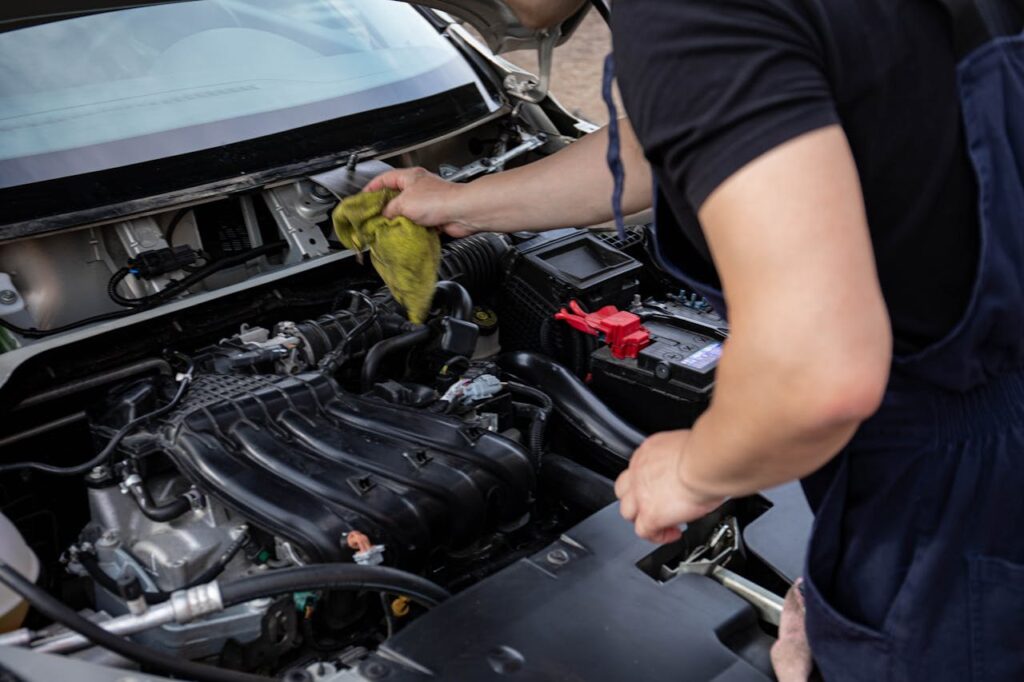 Mehaničar briše motor krpom prilikom provere stanja vozila.