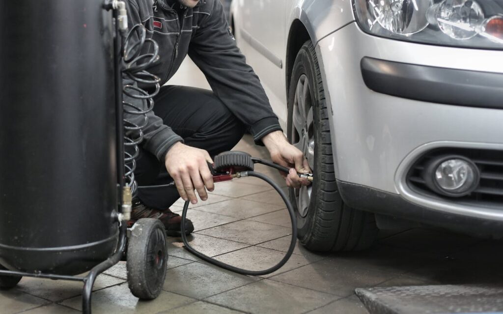 Majstor u servisu proverava i dopunjava pritisak u automobilskim gumama.